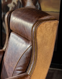 True Grit Executive Desk Chair in full-grain brown leather with gold-finish brass nail tacks and leather suede sides, showcasing ergonomic wingback design for superior comfort.