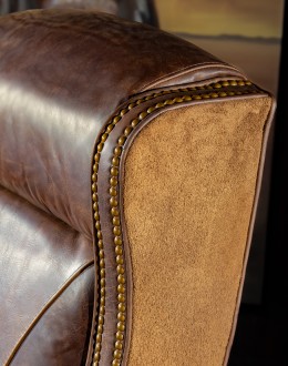 True Grit Executive Desk Chair in full-grain brown leather with gold-finish brass nail tacks and leather suede sides, showcasing ergonomic wingback design for superior comfort.