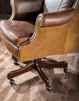 True Grit Executive Desk Chair in full-grain brown leather with gold-finish brass nail tacks and leather suede sides, showcasing ergonomic wingback design for superior comfort.