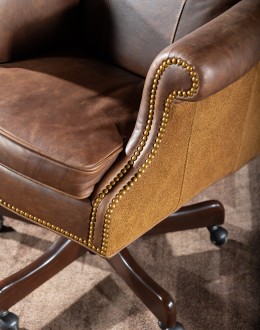 True Grit Executive Desk Chair in full-grain brown leather with gold-finish brass nail tacks and leather suede sides, showcasing ergonomic wingback design for superior comfort.