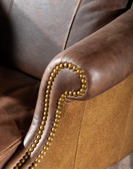 True Grit Executive Desk Chair in full-grain brown leather with gold-finish brass nail tacks and leather suede sides, showcasing ergonomic wingback design for superior comfort.